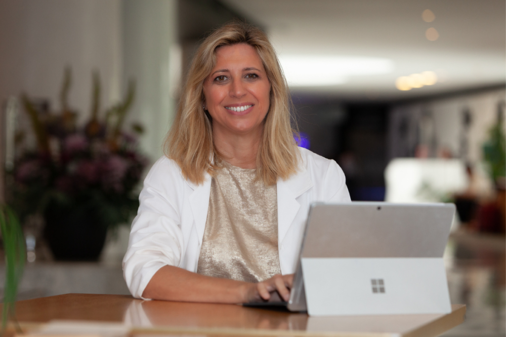 Patricia Tudó, con bata blanca, atendiendo desde su consulta con el portátil