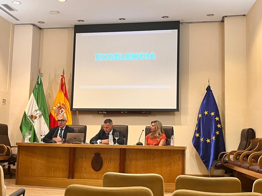 Patricia Tudó en la mesa presidencial de una jornada institucional, junto a otros dos ponentes